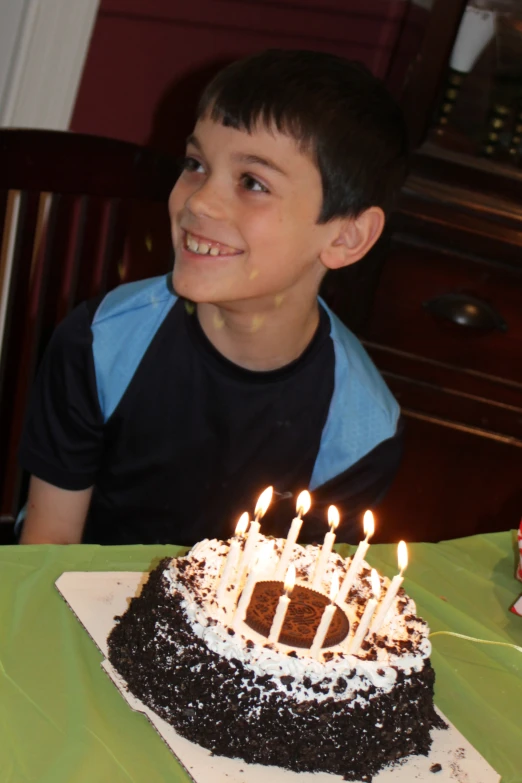 a little boy is sitting at a table in front of a cake