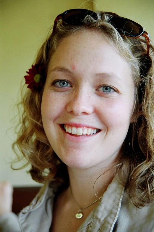 a smiling woman with sunglasses on her head