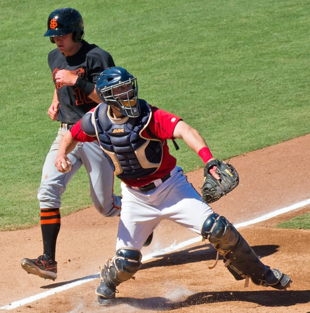 baseball game in progress, catcher is trying to catch ball that his opponent just pitched