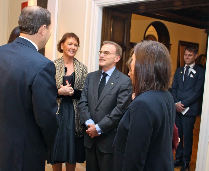 a group of people stand talking together and looking at one another