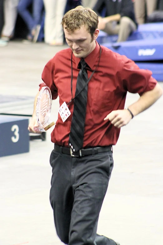 man in red shirt carrying tennis racket in hand