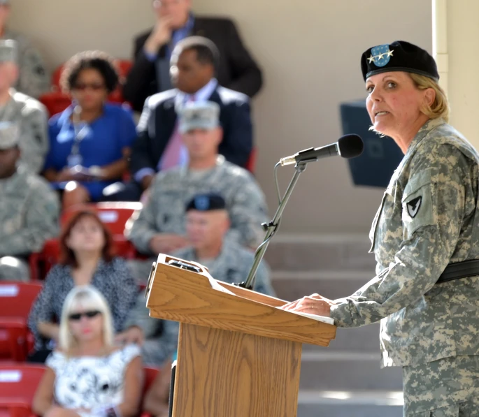 a woman in military clothing speaking at an auditorium