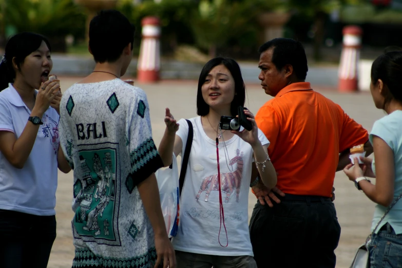 a group of asian people standing outside and talking to one another