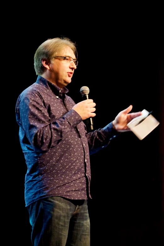 a man in glasses talking into a microphone
