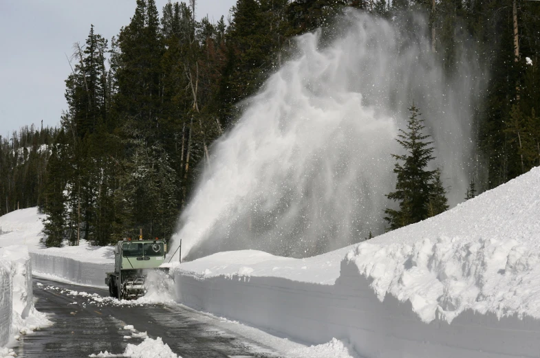 a truck drives next to piles of snow that are falling down