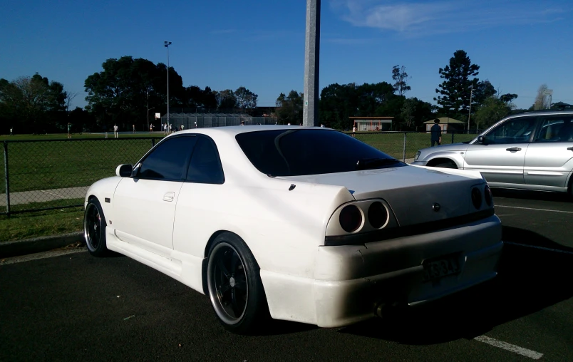 the rear of a white sports car parked in a lot