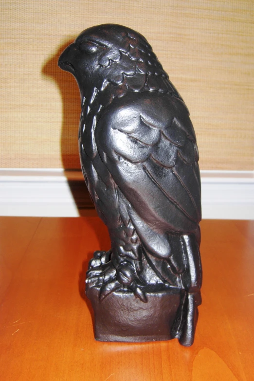 a large metal bird sitting on top of a wooden table