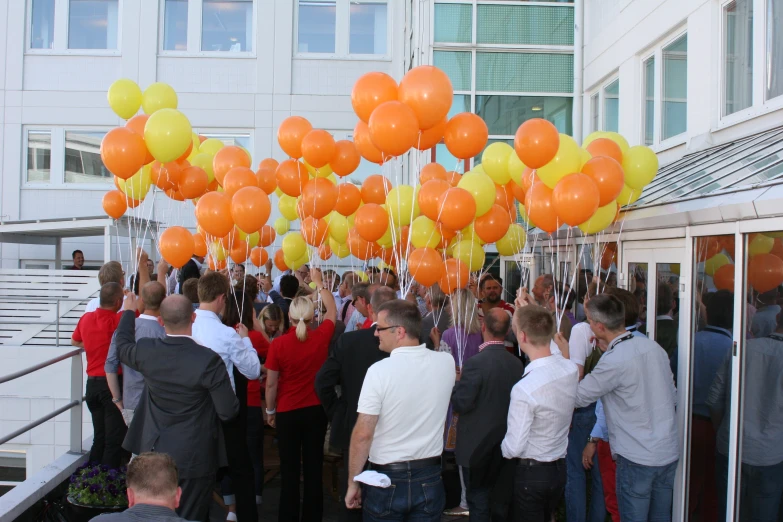 a group of people standing in a large room with lots of yellow and orange balloons