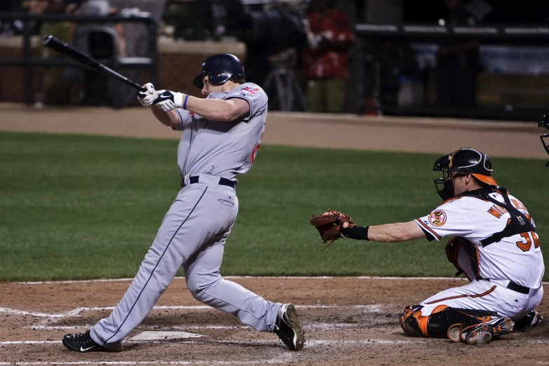 baseball batter hitting the ball with a catcher and umpire behind him