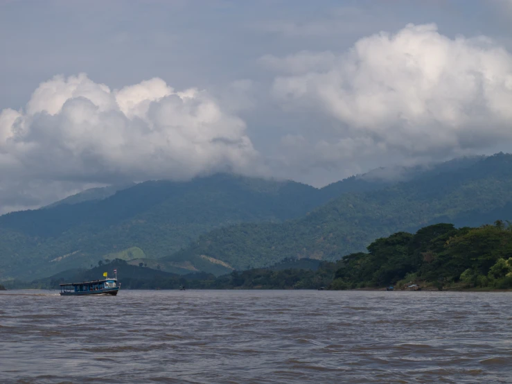 the boat is traveling down the river in front of the mountains