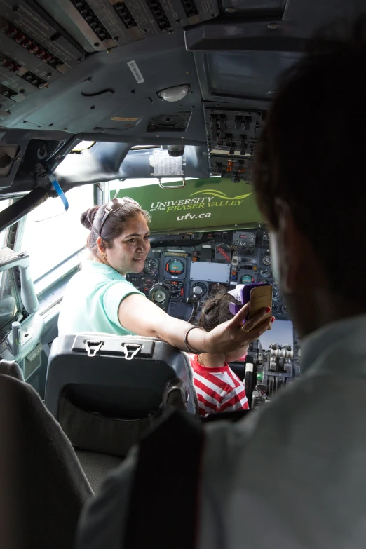 woman with cell phone in front of pilots sitting in cockpit