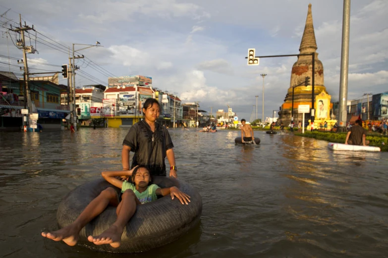 two people riding in an inflatable tube through flooded street