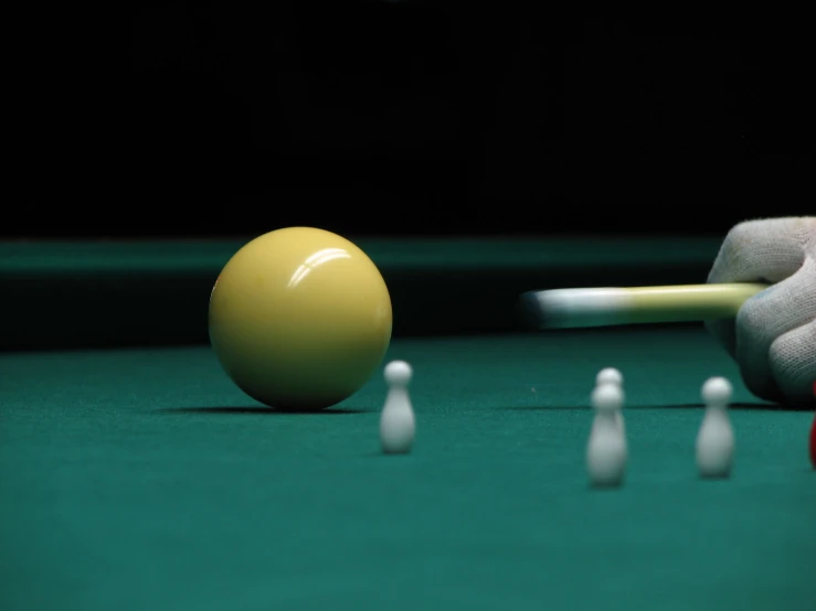 one person holding up a yellow ball on top of a pool table