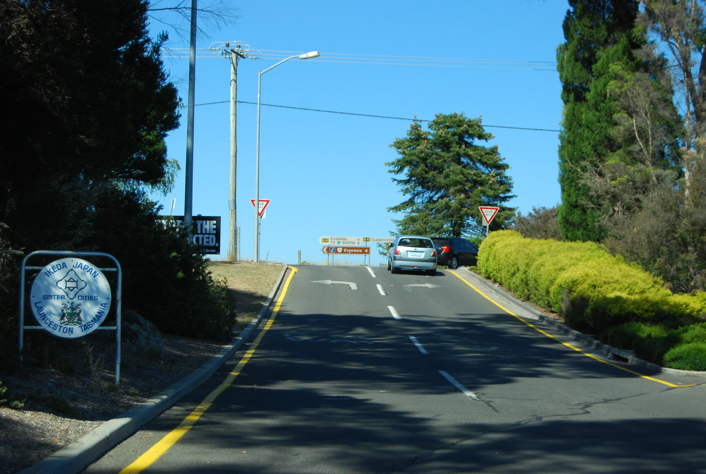 two cars are driving on the highway near some trees