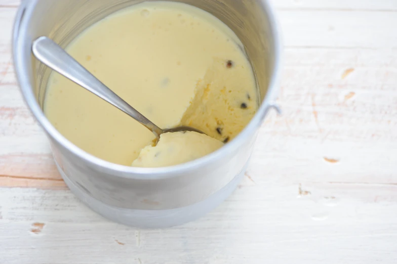 a silver measuring cup with some cream on top