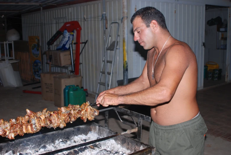 a shirtless man preparing food on top of a grill