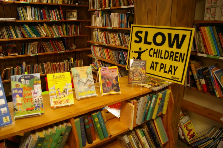 a yellow sign that says slow children at play is in front of several bookshelves