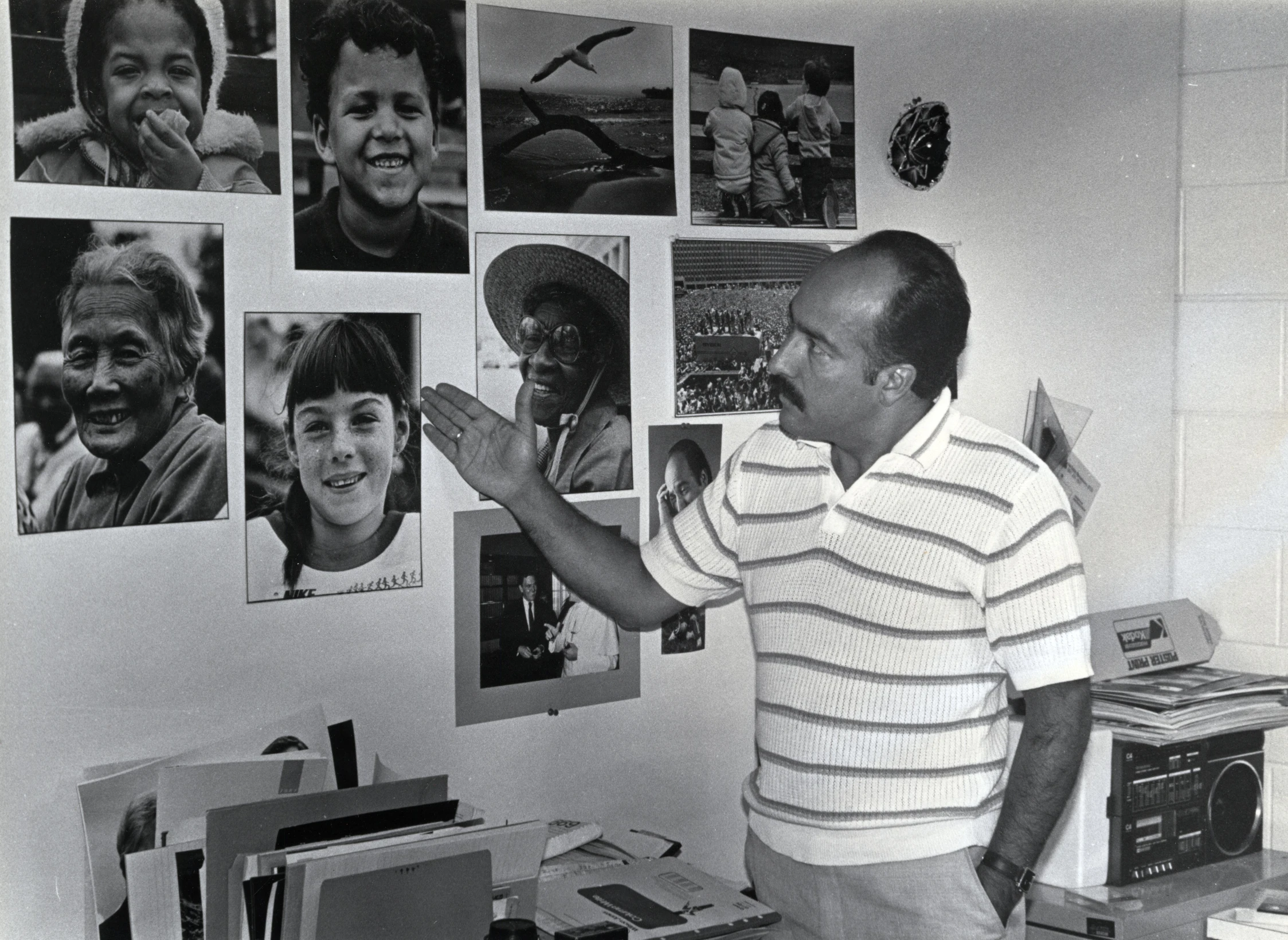an african man standing by a wall with several pictures on it