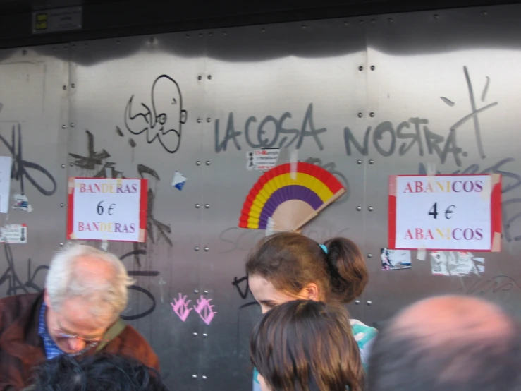 a bunch of people standing near a wall with graffiti on it