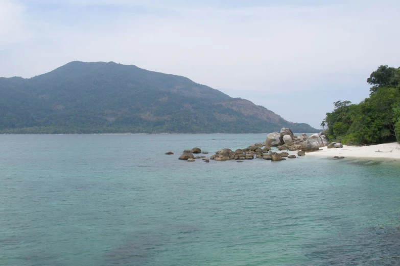 some clear blue water rocks trees and mountains