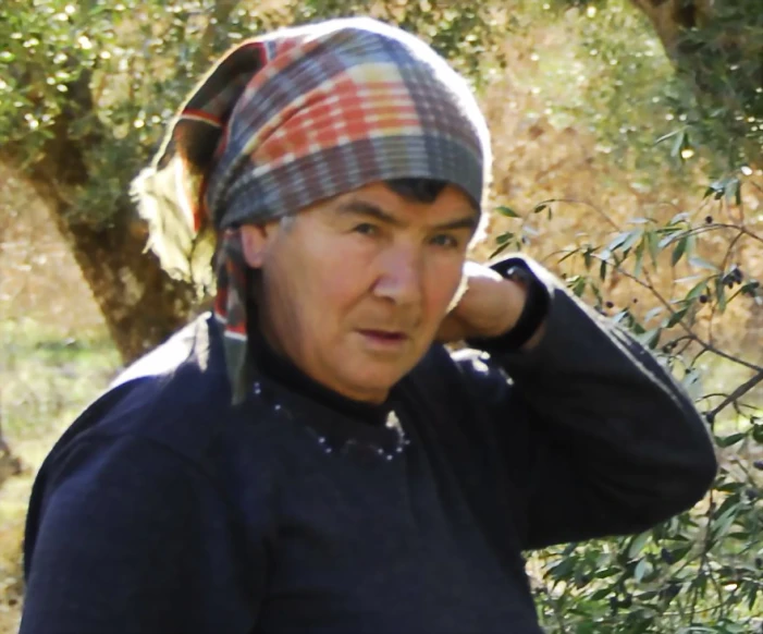 an older man wearing a hat and scarf on the phone