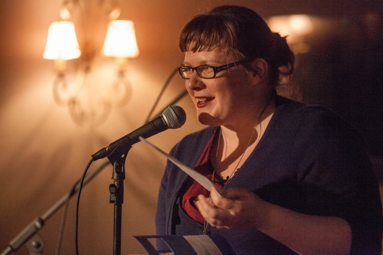 woman speaking at microphone in dimly lit room