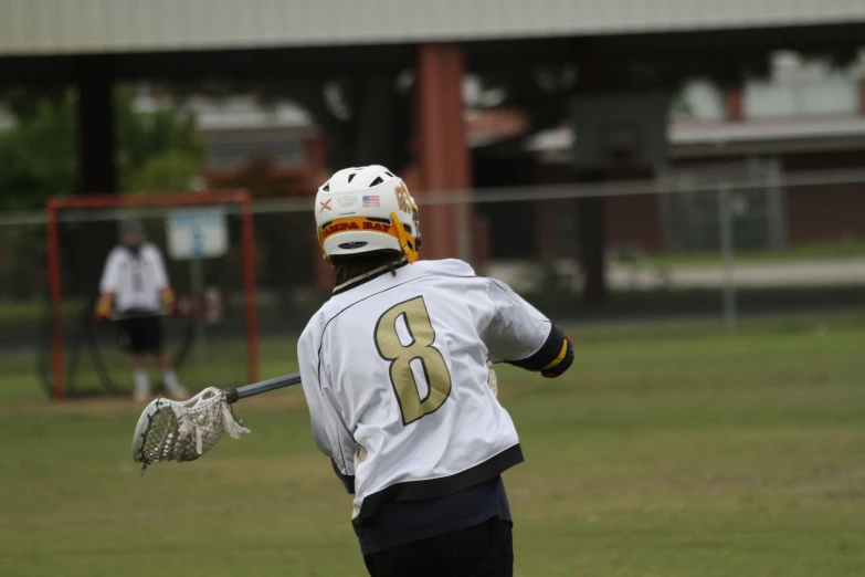 a person in a lacrosse uniform holds a bat