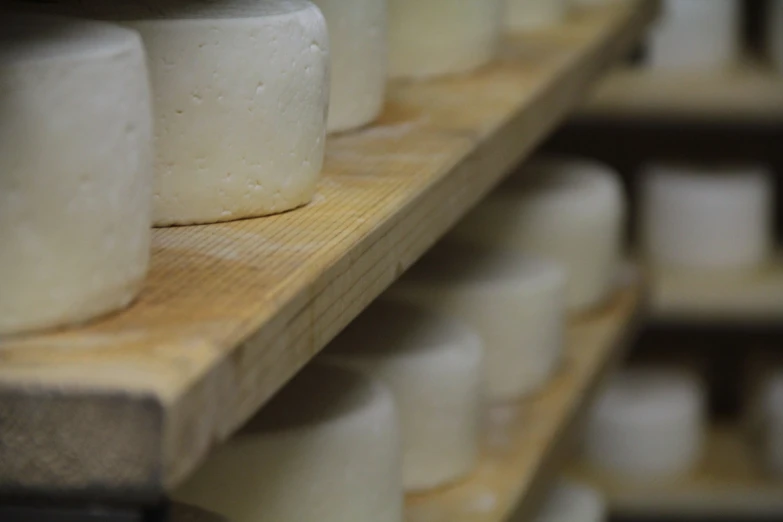 cheese is stacked on a wooden shelf ready to be cooked