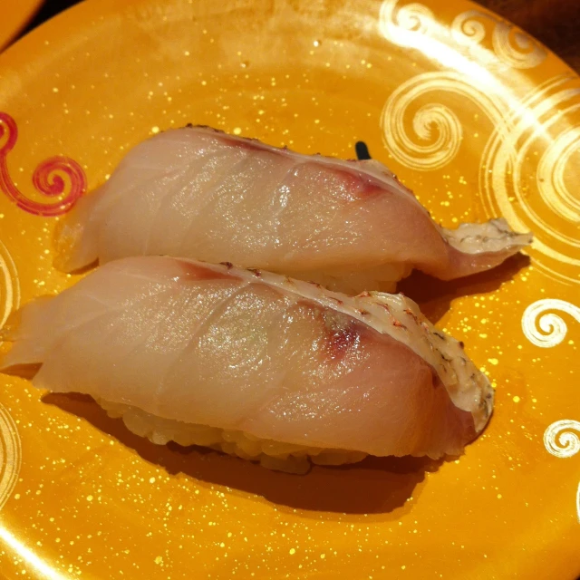 two sushi on a yellow plate with a swirly pattern