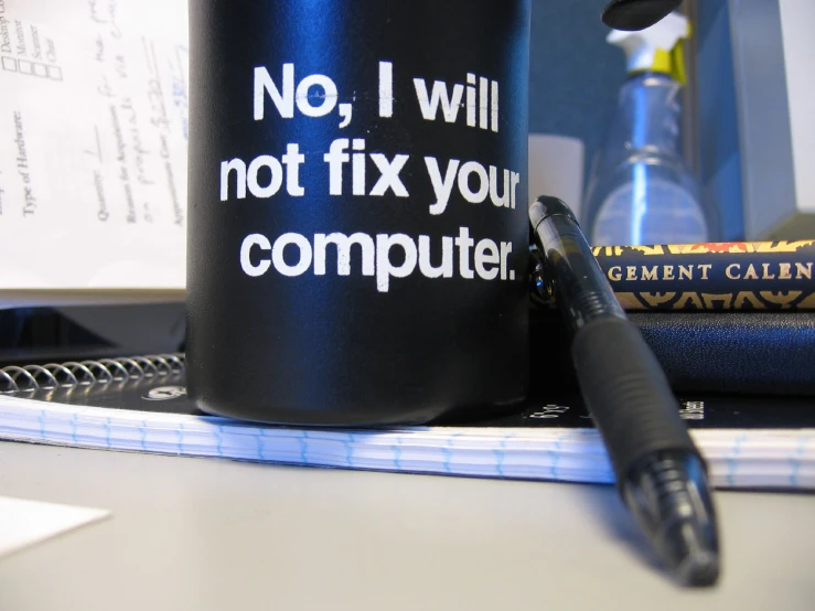 a mug next to an open notebook and a pen