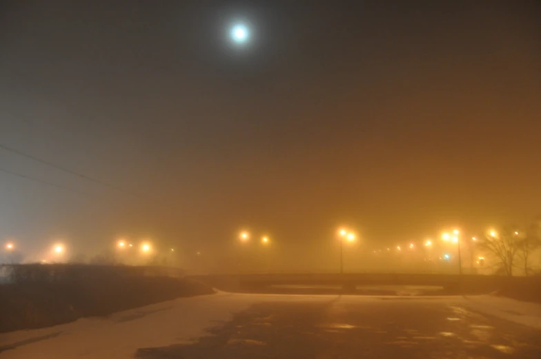 fog covers the ground, some lights over a street