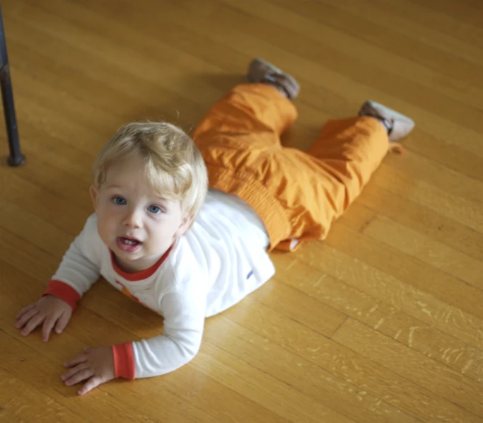 a baby is laying down with his head on the floor