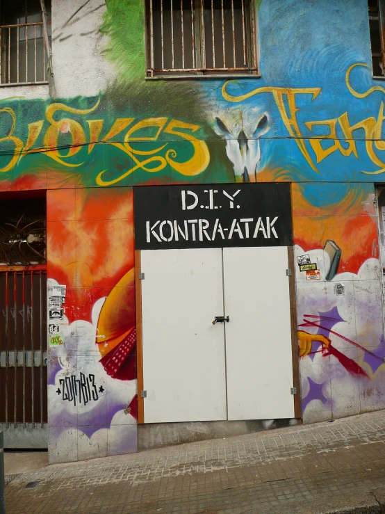 a building with graffiti on it with white doors and one doorway