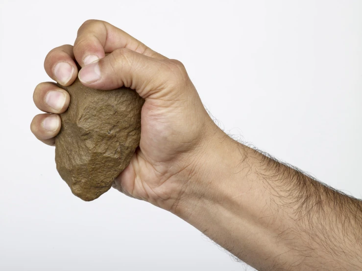 a hand holding a piece of brown rock