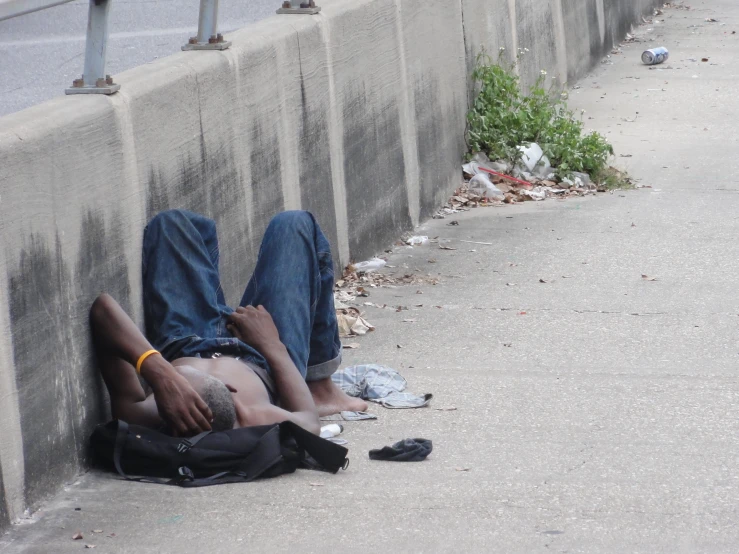 a person lying on the side of a road with a backpack