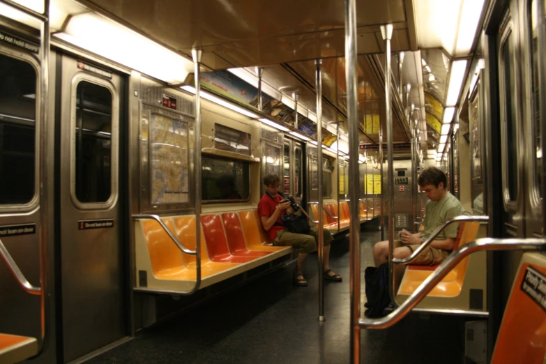 three people on a subway train sitting down