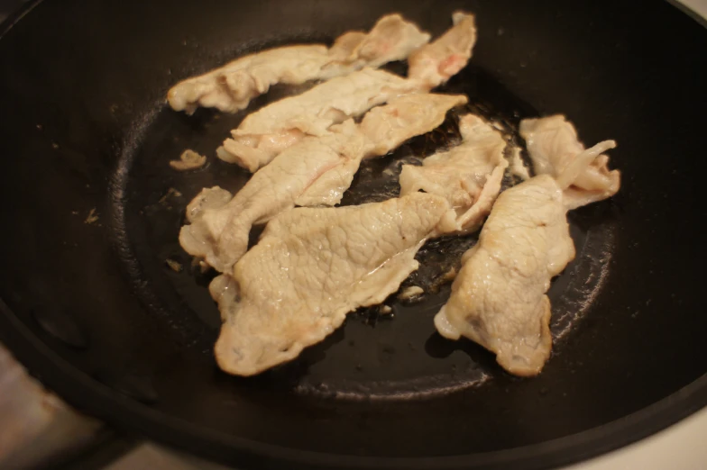 several chicken slices cooking in a set on top of a stove