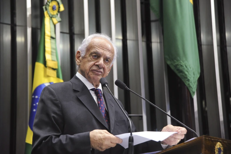 the man is reading a paper in front of two flags