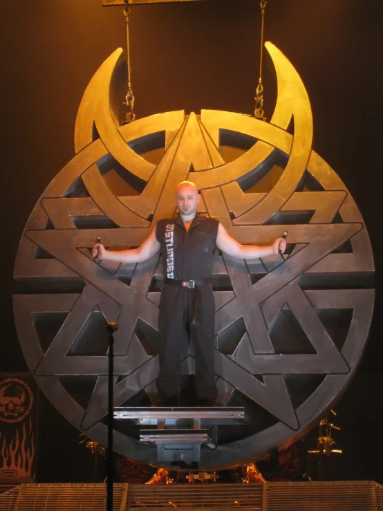 man stands on stage behind large circular structure