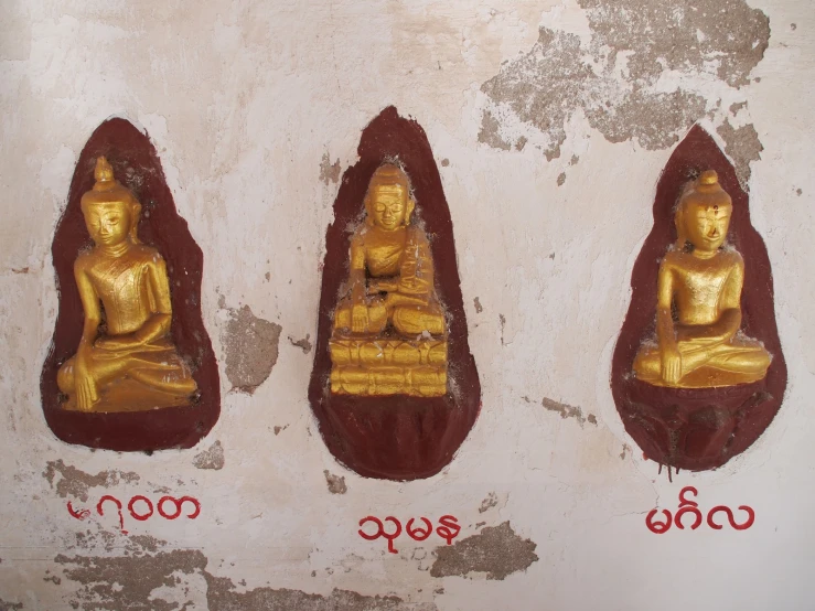 three gold buddhas in their own wall with red numbers