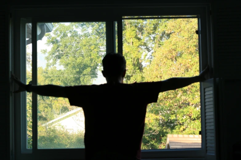 a person standing in front of a window with their arms out and arms outstretched