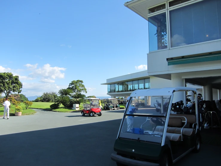 a person standing next to a green golf cart and a red car