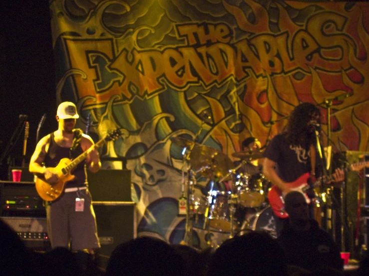 three musicians are in front of an artisticly painted backdrop