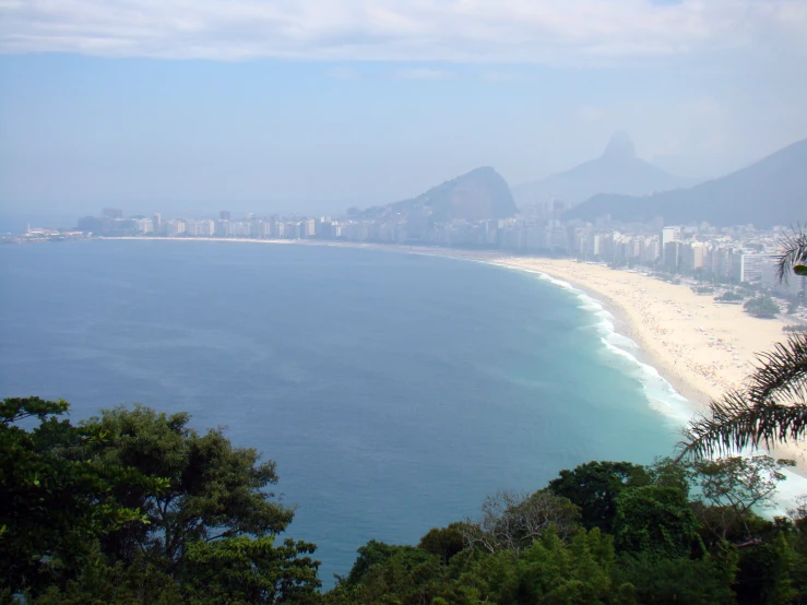 the view from the top of a hill at the beach in front of a city