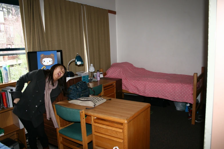 a woman in the bedroom smiles next to a desk and a bed