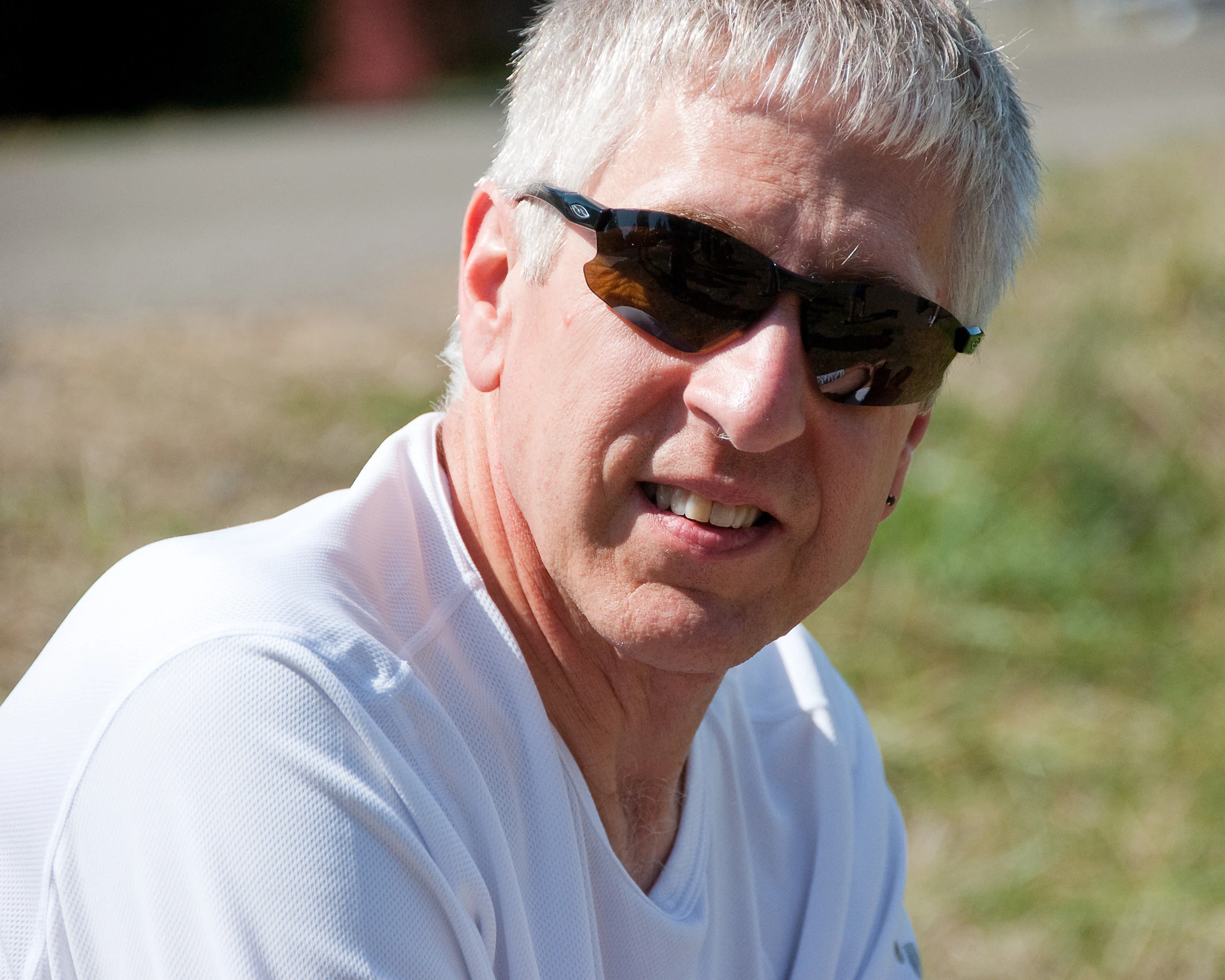 a man in white shirt and sunglasses looking at the camera