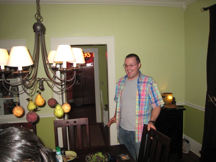 a man in plaid shirt standing next to light fixture