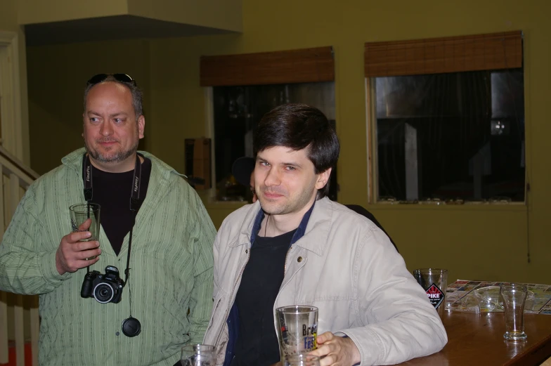 two men posing for a picture with their drinks