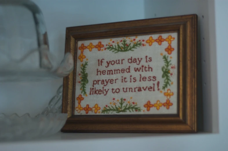 cross stitch picture displayed in brown frame with saying