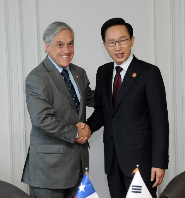 two men shake hands while standing next to flags